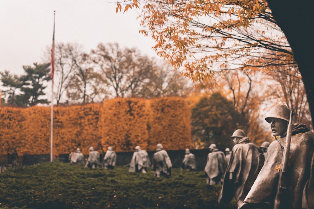 people sitting on green grass field near brown trees during daytime