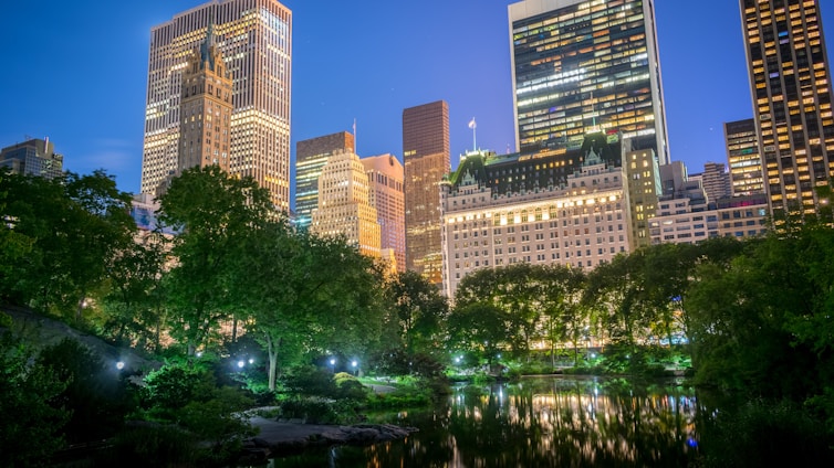 A serene view of the Runwal Lands End residential towers illuminated at dusk, surrounded by lush greenery.