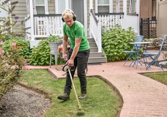 man in green t-shirt and black pants holding black and brown shovel