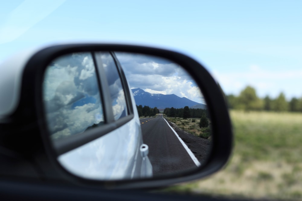 car side mirror showing road during daytime