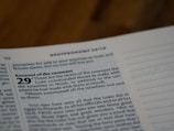 A close-up of a page from a Bible, focusing on Deuteronomy 29, which discusses the renewal of the covenant. The text is printed in a bold, clear font against a light-colored page. The page appears to be in a study or reading environment.