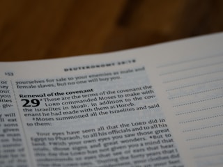 A close-up of a page from a Bible, focusing on Deuteronomy 29, which discusses the renewal of the covenant. The text is printed in a bold, clear font against a light-colored page. The page appears to be in a study or reading environment.