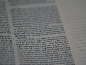 An open book with text printed on both visible pages. The left page contains paragraphs with varying sizes of text, and some words are in bold. The right page has sections of blank lines that appear to be for notes or annotations. The text is in English.