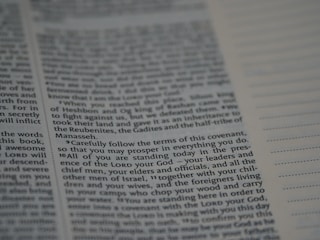 An open book with text printed on both visible pages. The left page contains paragraphs with varying sizes of text, and some words are in bold. The right page has sections of blank lines that appear to be for notes or annotations. The text is in English.