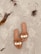 A close-up of colorful sandals displayed on a wooden deck with a beach in the background.