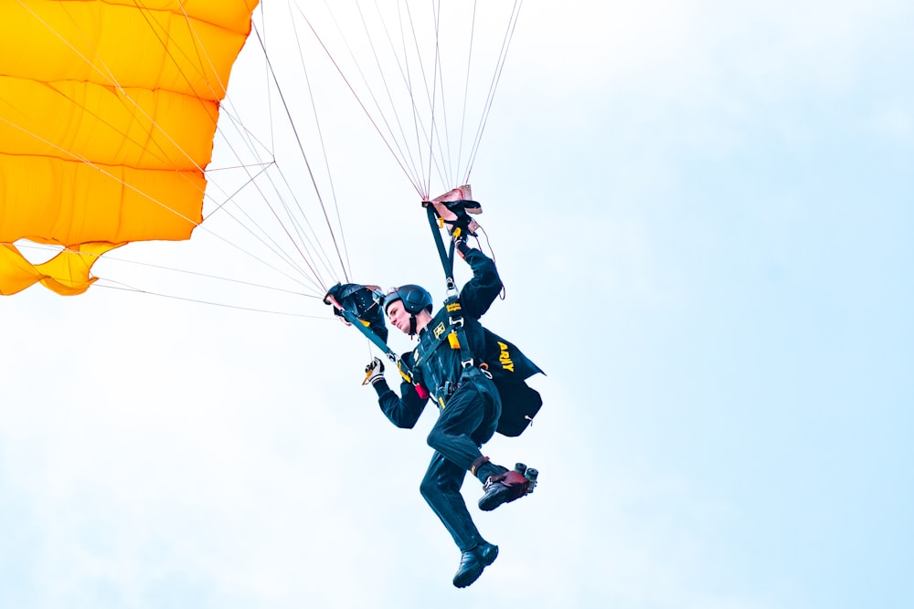 man in blue jacket and black pants with yellow parachute