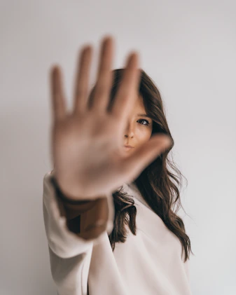 woman in white shirt covering her face with her hand
