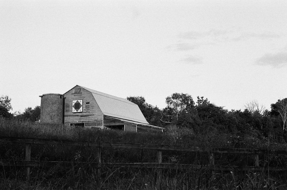 grayscale photo of wooden house on grass field