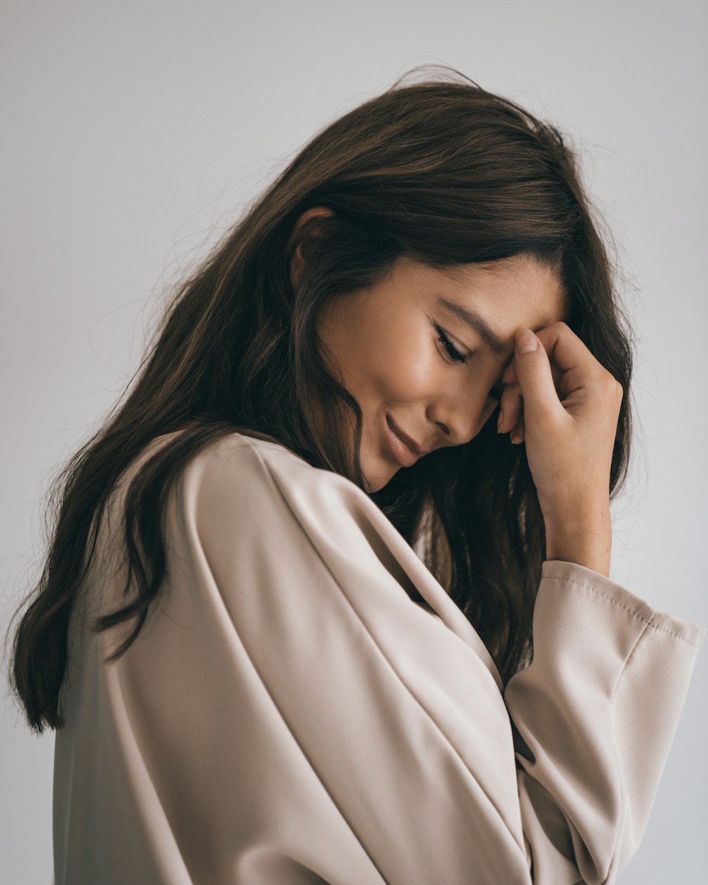 woman in white long sleeve shirt covering her face with her hand