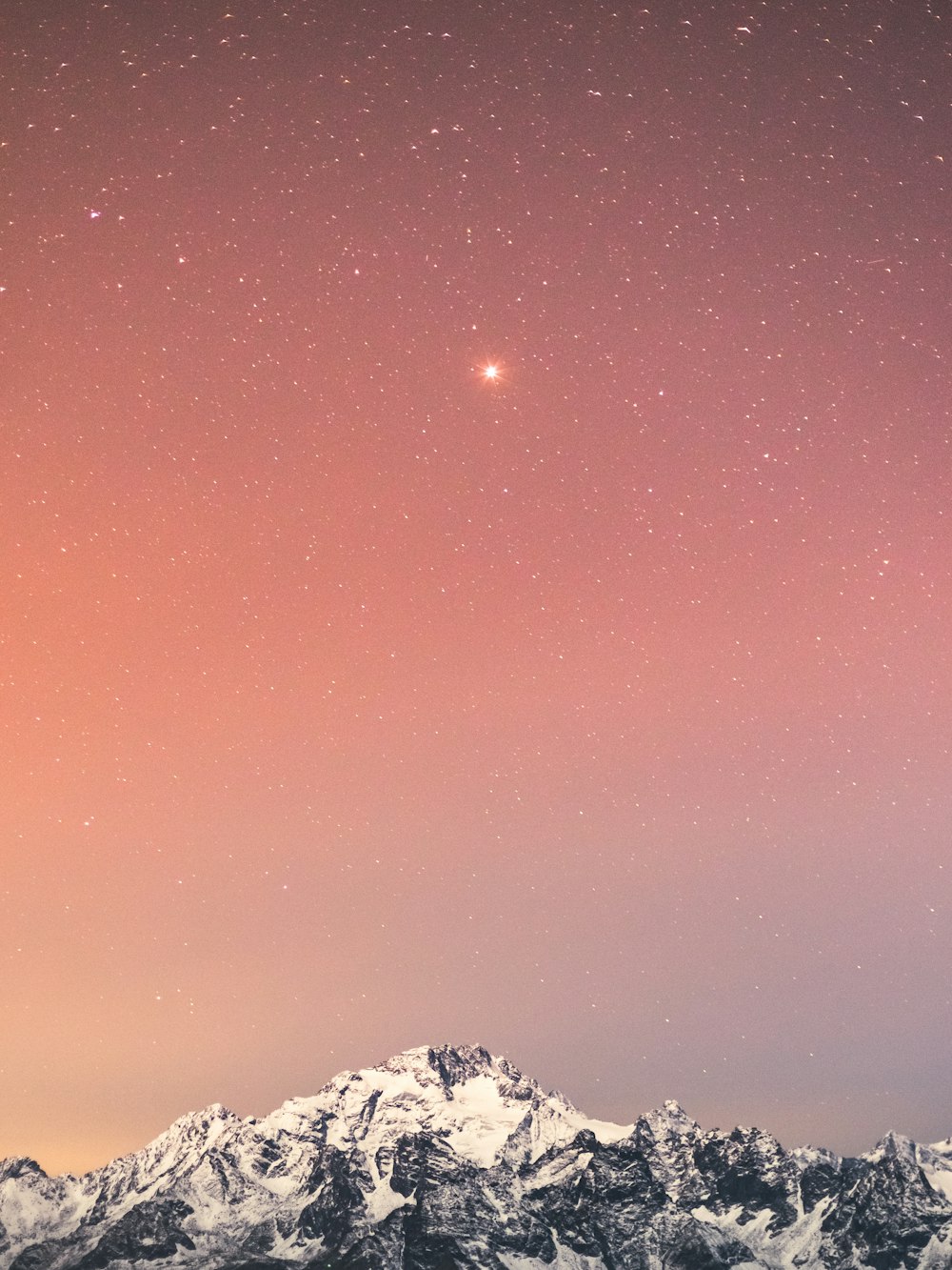 夜の星空と青空の下で雪に覆われた山