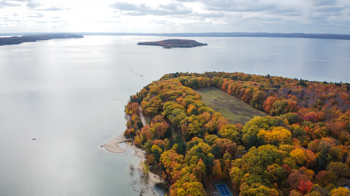 An aerial view of a wooded point in autumn colors, surrounded by water, near Traverse City