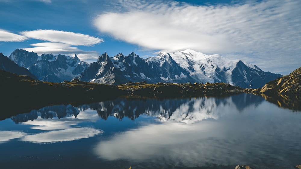 snow covered mountain near lake under cloudy sky during daytime