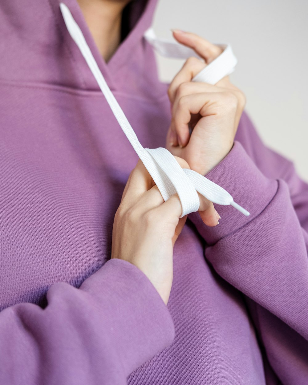 person in purple long sleeve shirt holding white plastic clothes hanger