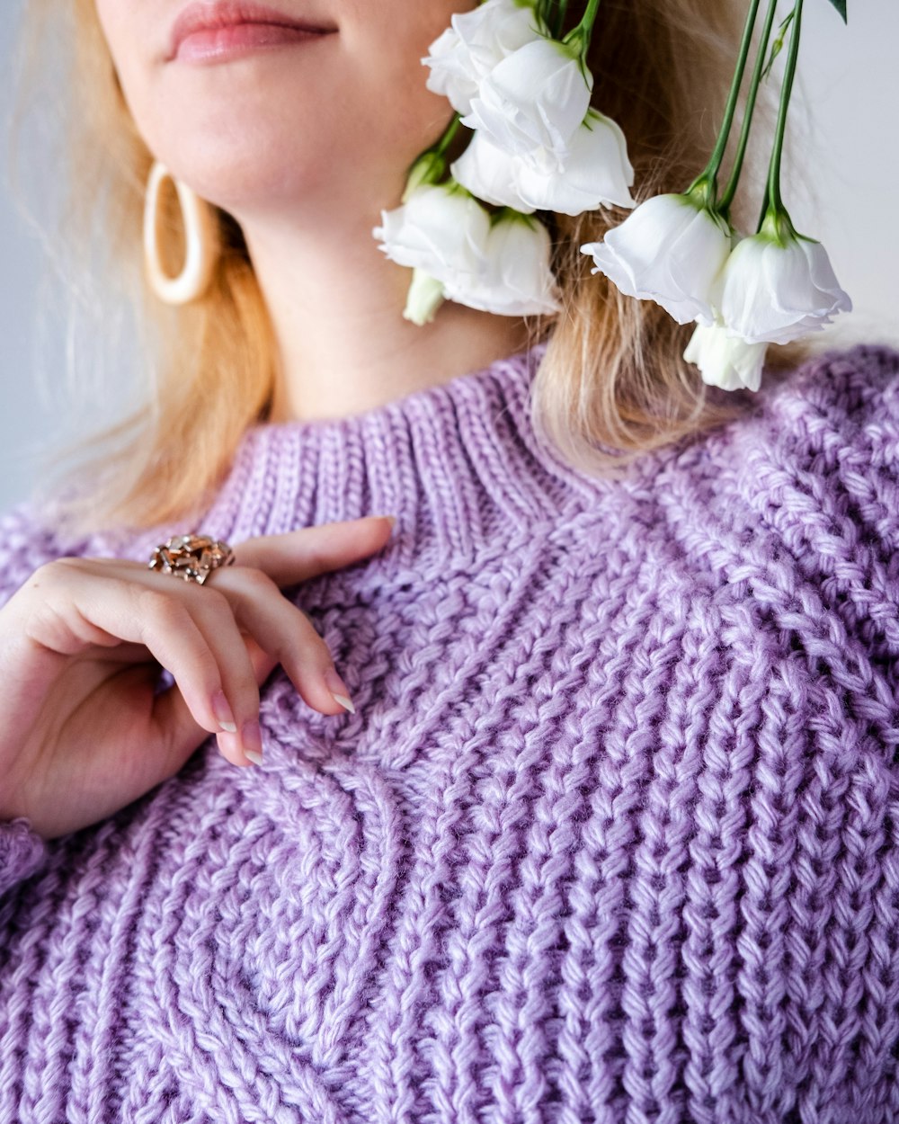 woman in white knit sweater holding white rose