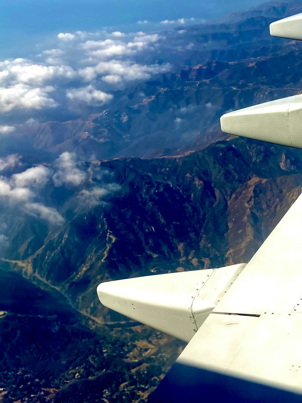 Ala blanca del avión sobre las montañas durante el día