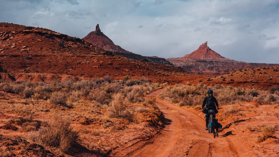 man in black jacket riding bicycle on brown dirt road during daytime