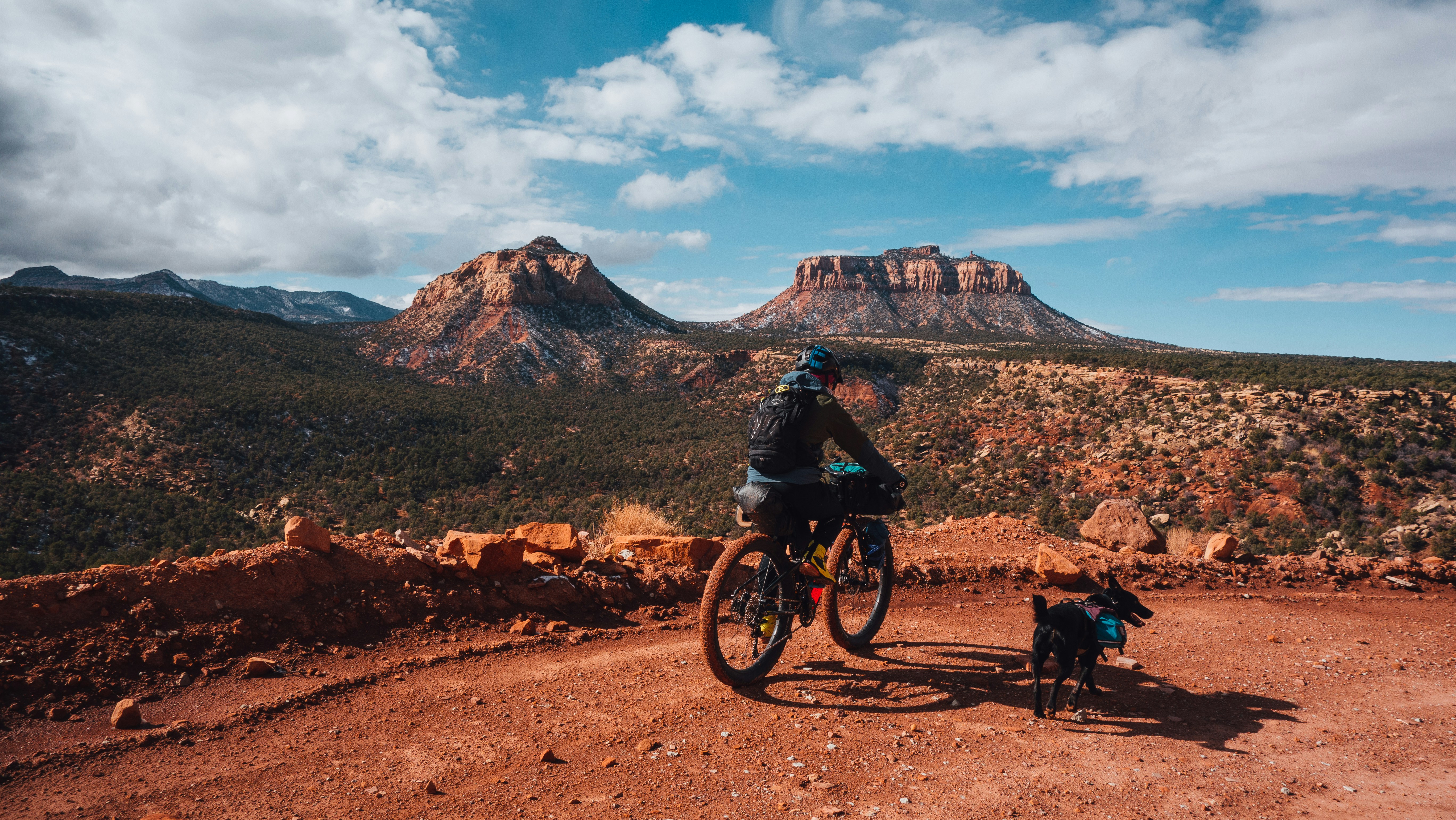 man riding bicycle on dirt road near mountain during daytime