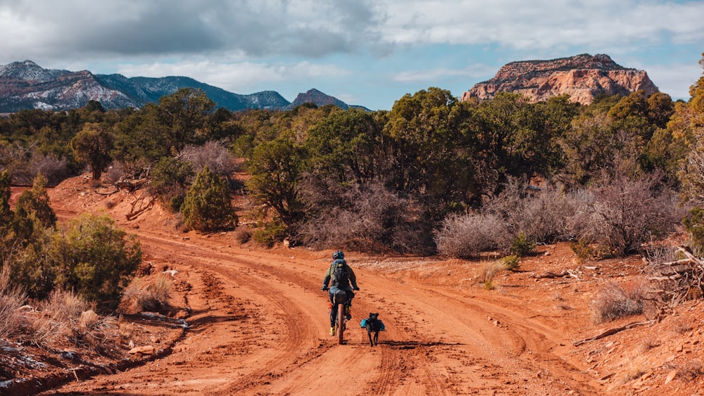 man riding bicycle on dirt road during daytime