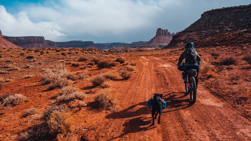 people riding bicycle on brown dirt road during daytime