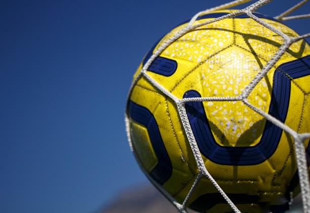 A dynamic shot of a soccer ball hitting the net in a bright stadium.