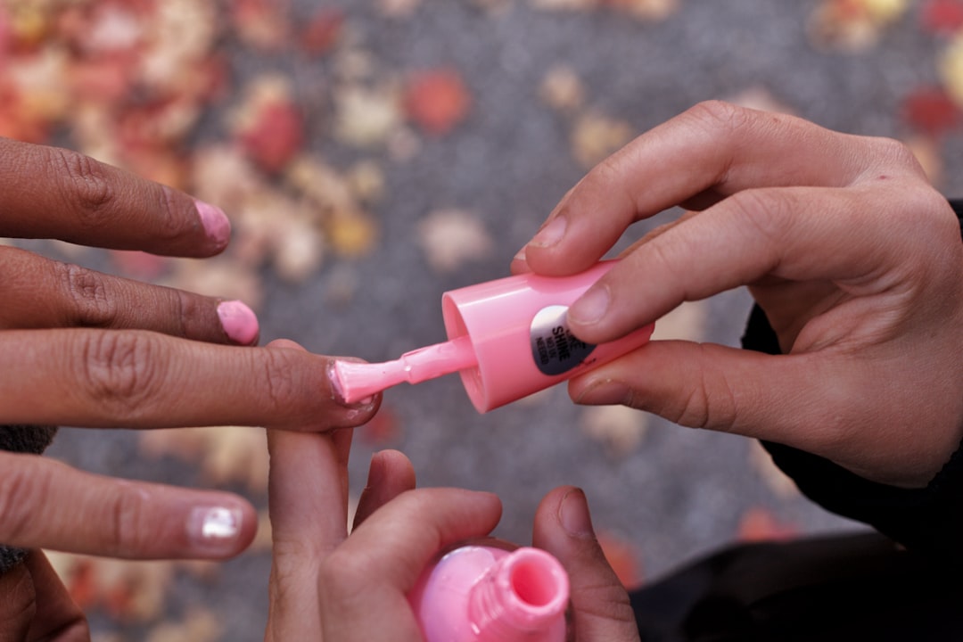 person holding pink plastic bottle