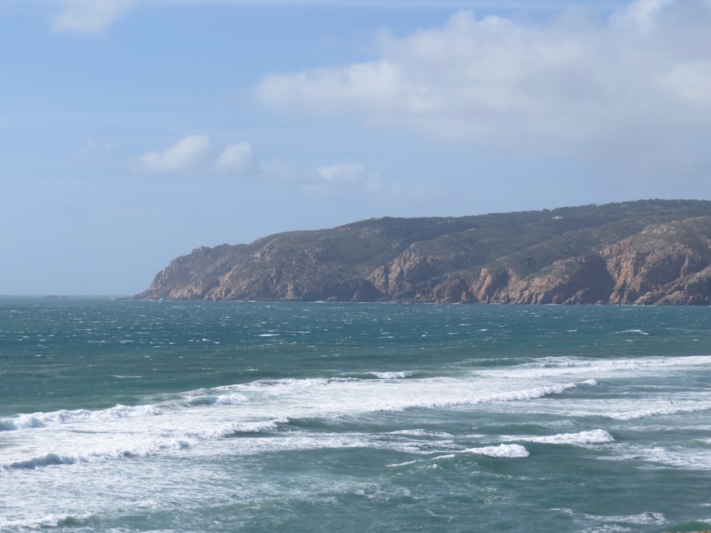 green and brown mountain beside sea during daytime