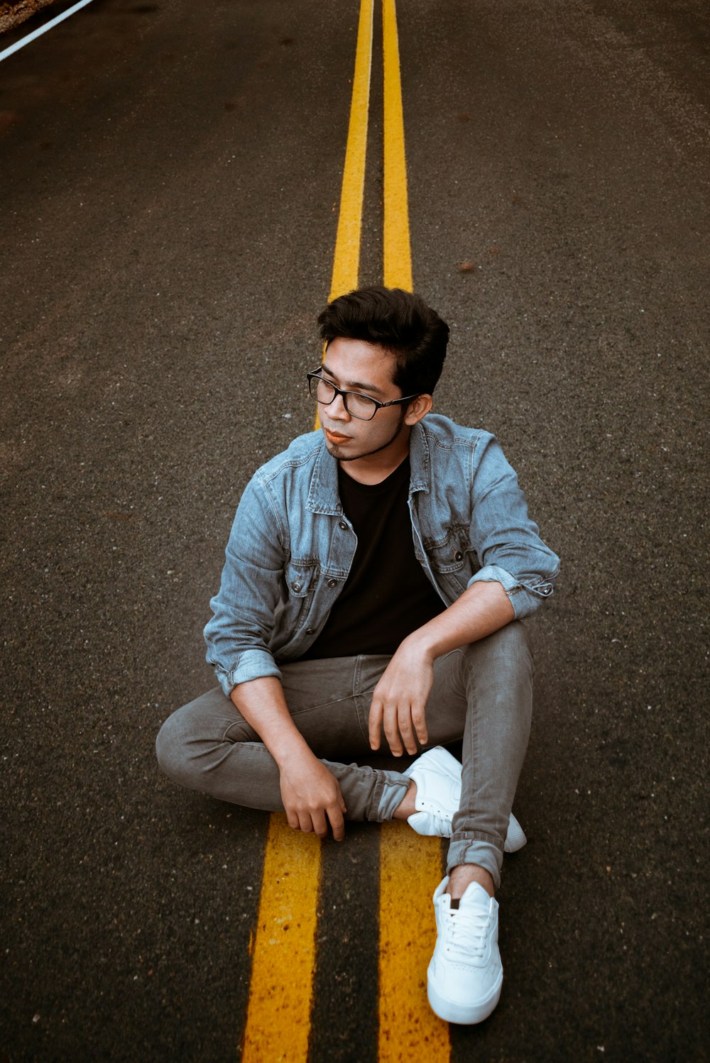 man in blue denim jacket sitting on yellow plastic chair