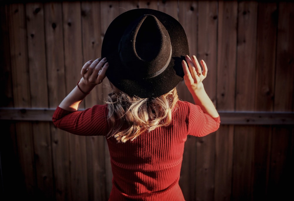 검은 페도라 모자를 쓰고 빨간 긴 소매 셔츠를 입은 여자