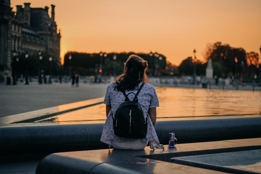 woman in black and white shirt sitting on bench during sunset
