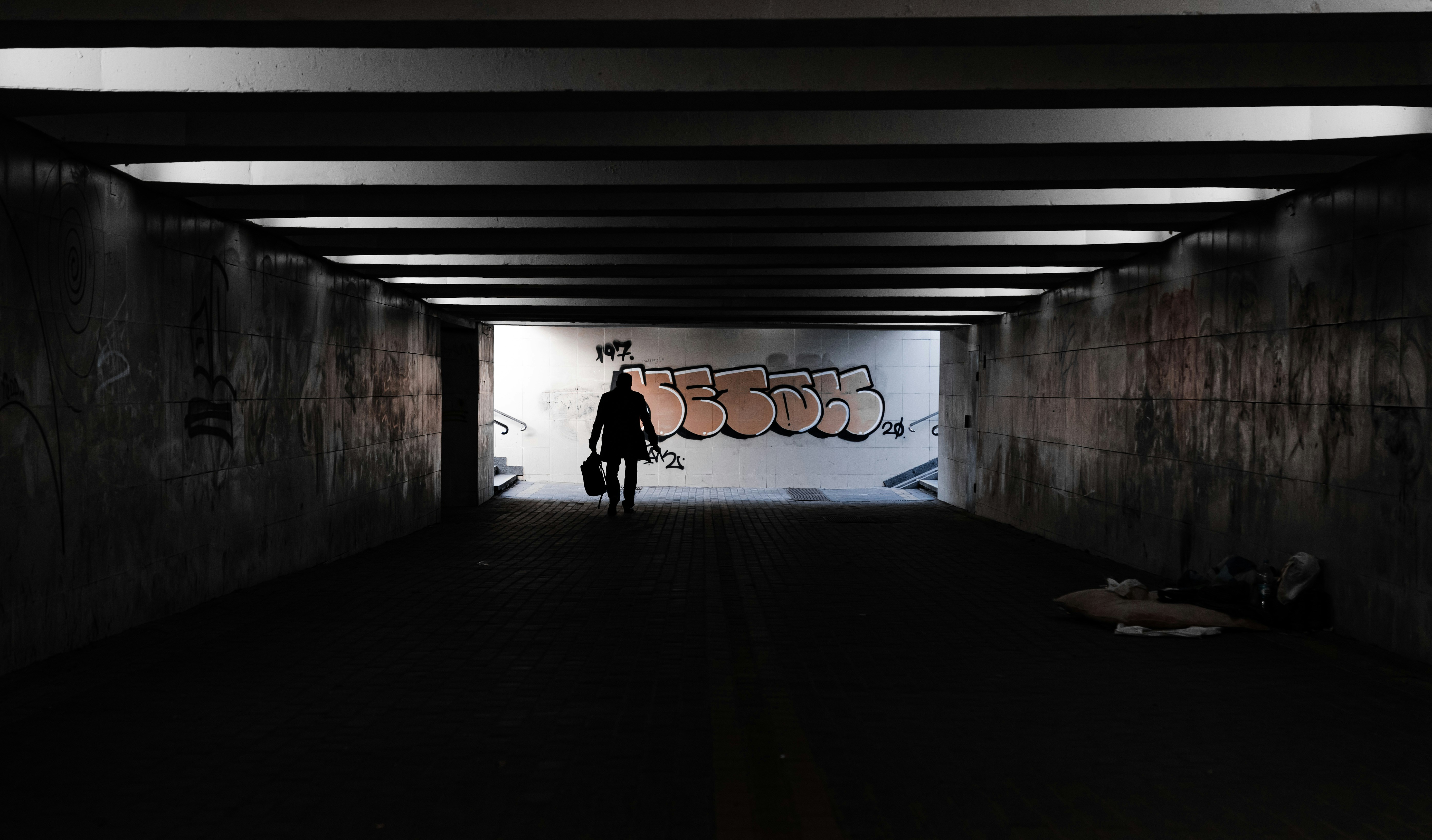 silhouette-of-person-walking-on-tunnel-during-daytime