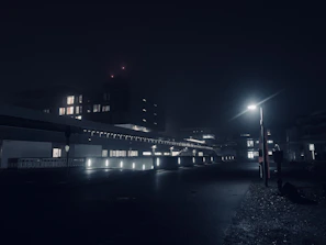 A moody, dimly lit urban nightscape with a shallow depth of field capturing glowing streetlights.