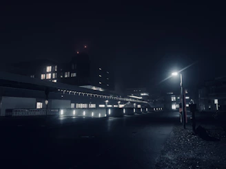 A moody, dimly lit urban nightscape with a shallow depth of field capturing glowing streetlights.