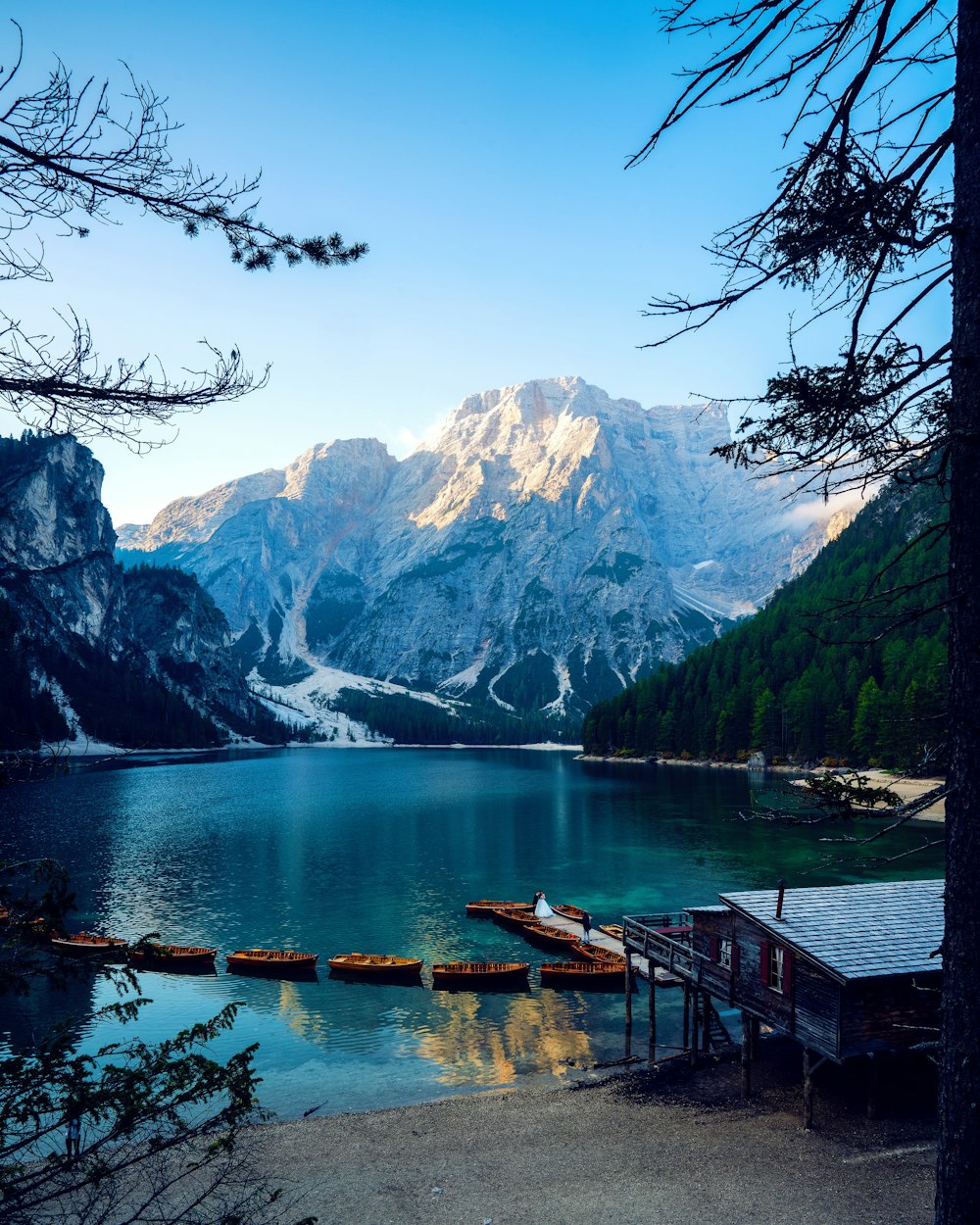 Muelle de madera marrón en el lago cerca de la montaña cubierta de nieve durante el día