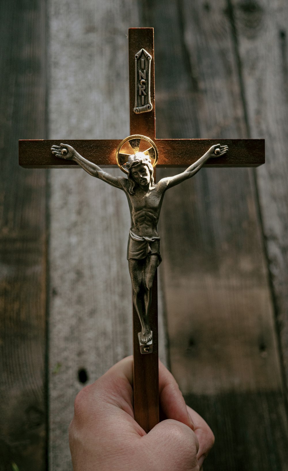 gold crucifix on brown wooden fence