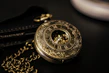 An elegant silver pocket watch lying on a rustic wooden table.