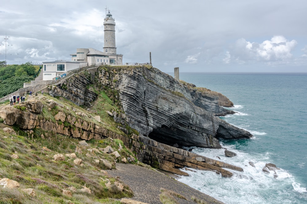 Faro blanco en un acantilado junto al mar durante el día