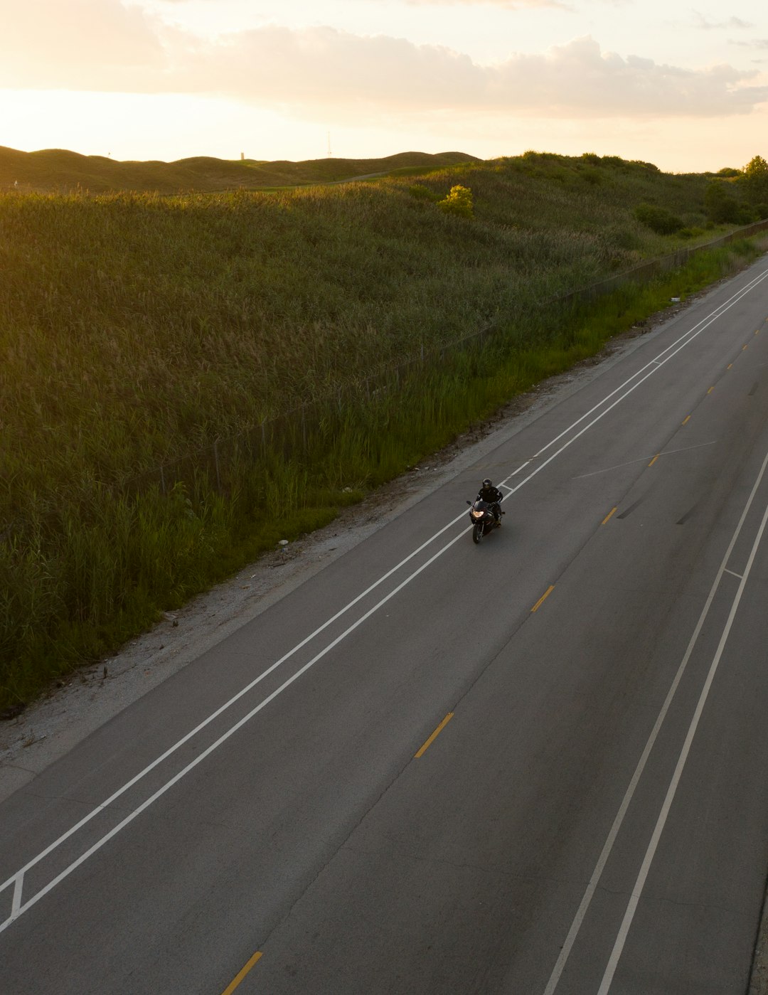 black car on road between green grass field during daytime