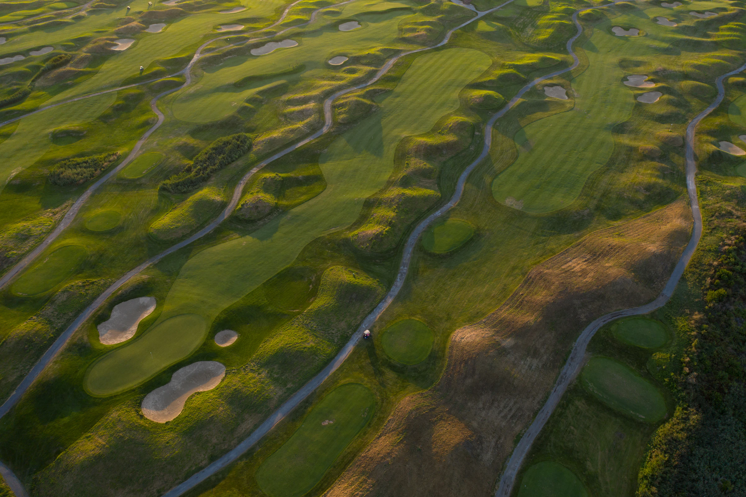 Golden-hour aerial view of a fairway winding through the course