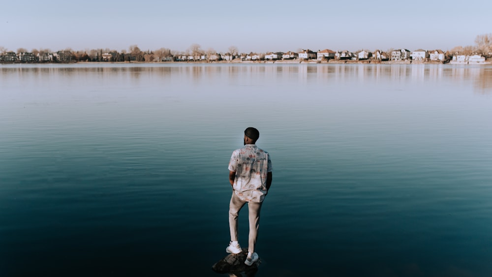 man in gray shirt standing on body of water during daytime