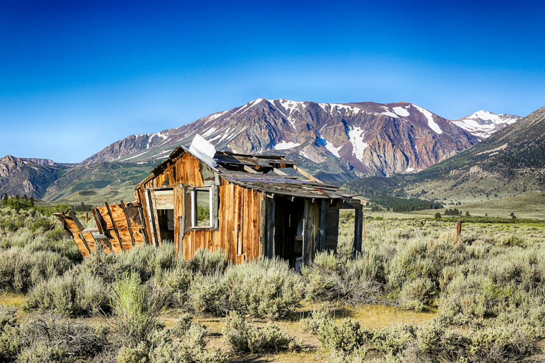 brown wooden house near mountain under blue sky during daytime