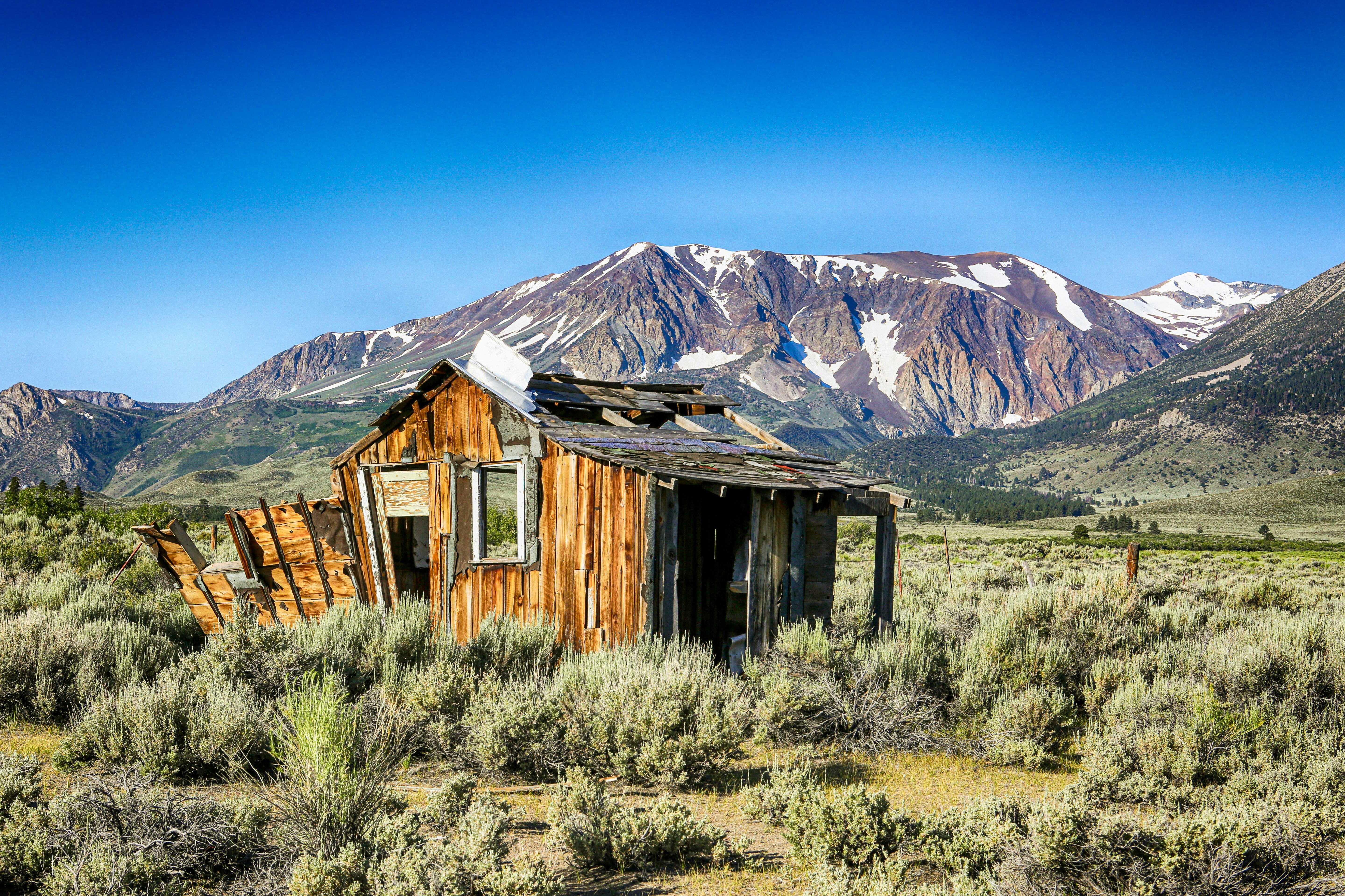 brown wooden house near mountain under blue sky during daytime