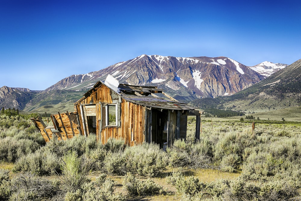 casa di legno marrone vicino alla montagna sotto il cielo blu durante il giorno
