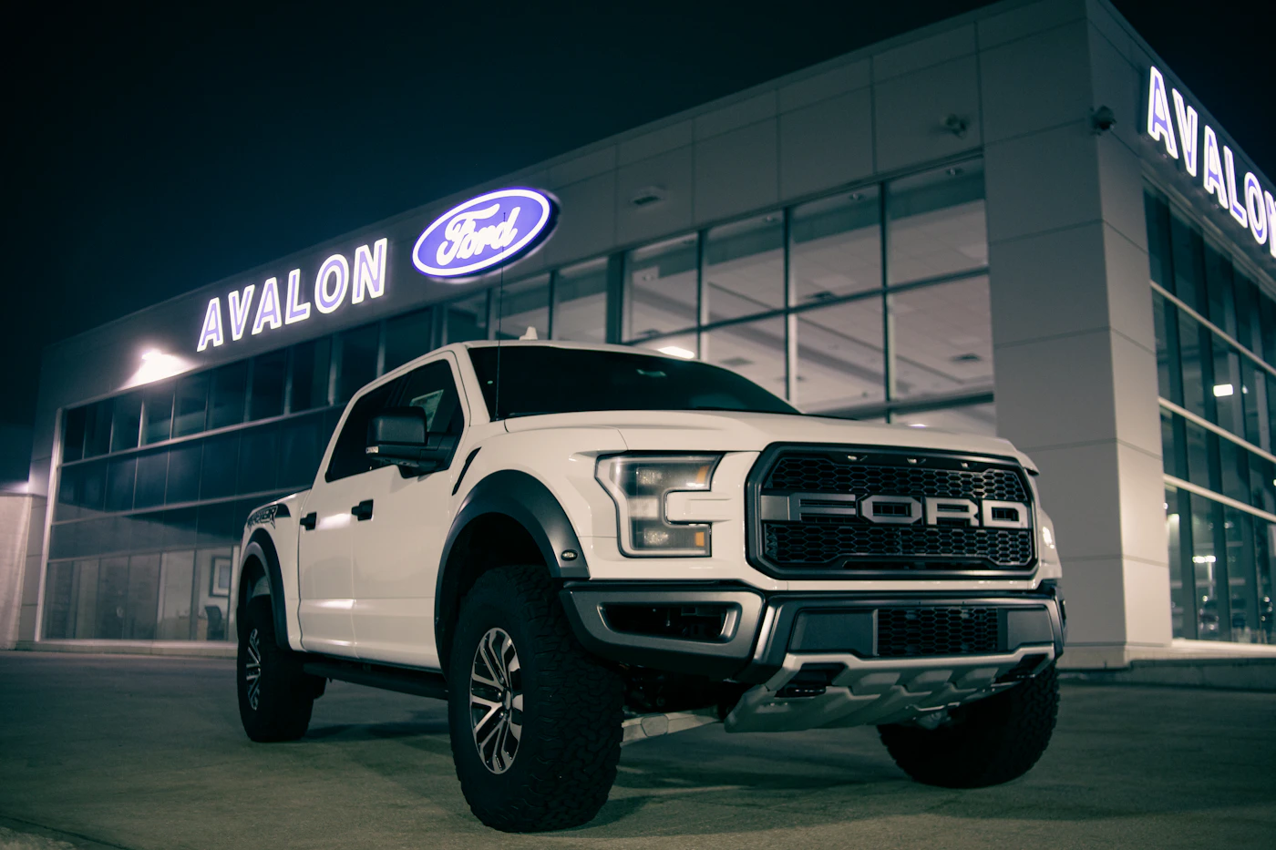 White pickup truck outside a dealership at night, photographed by Erik Mclean