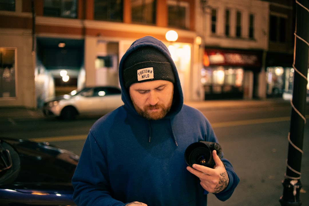 man in black hoodie holding black dslr camera