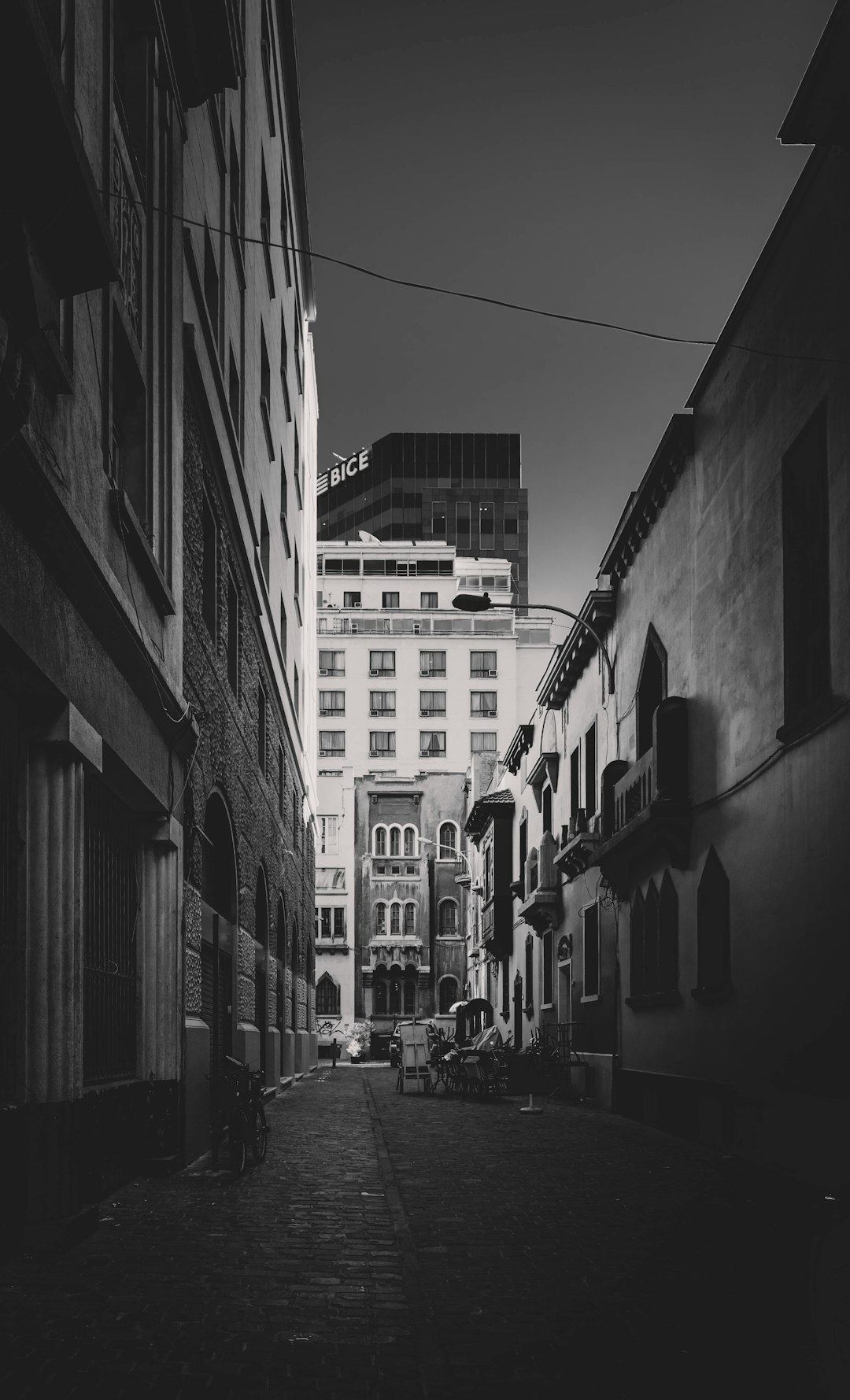 grayscale photo of cars parked beside building