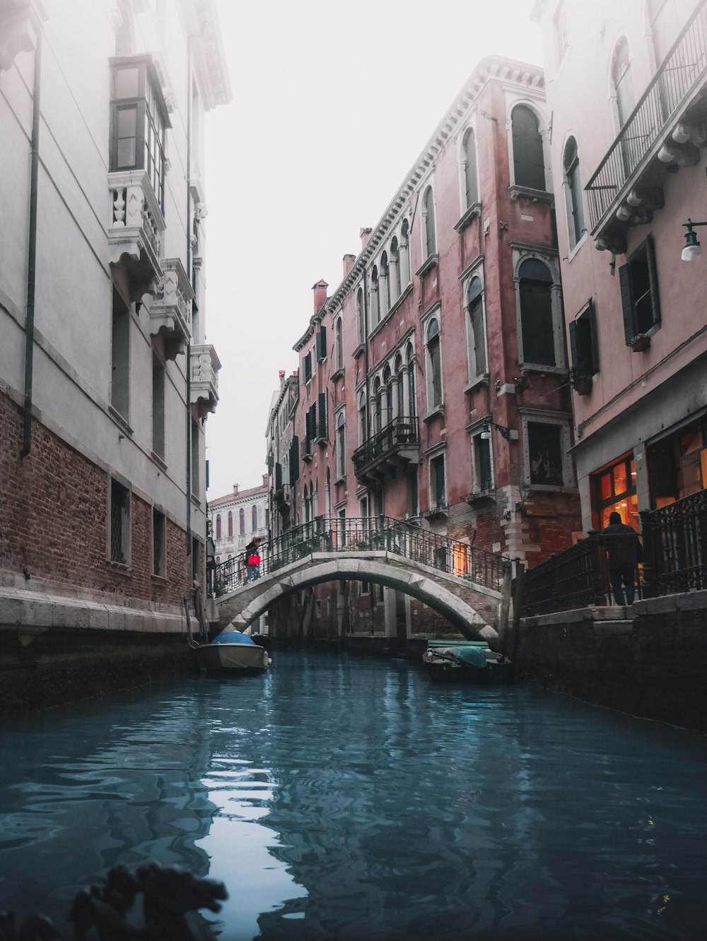 Barco blanco y azul en el río entre edificios durante el día