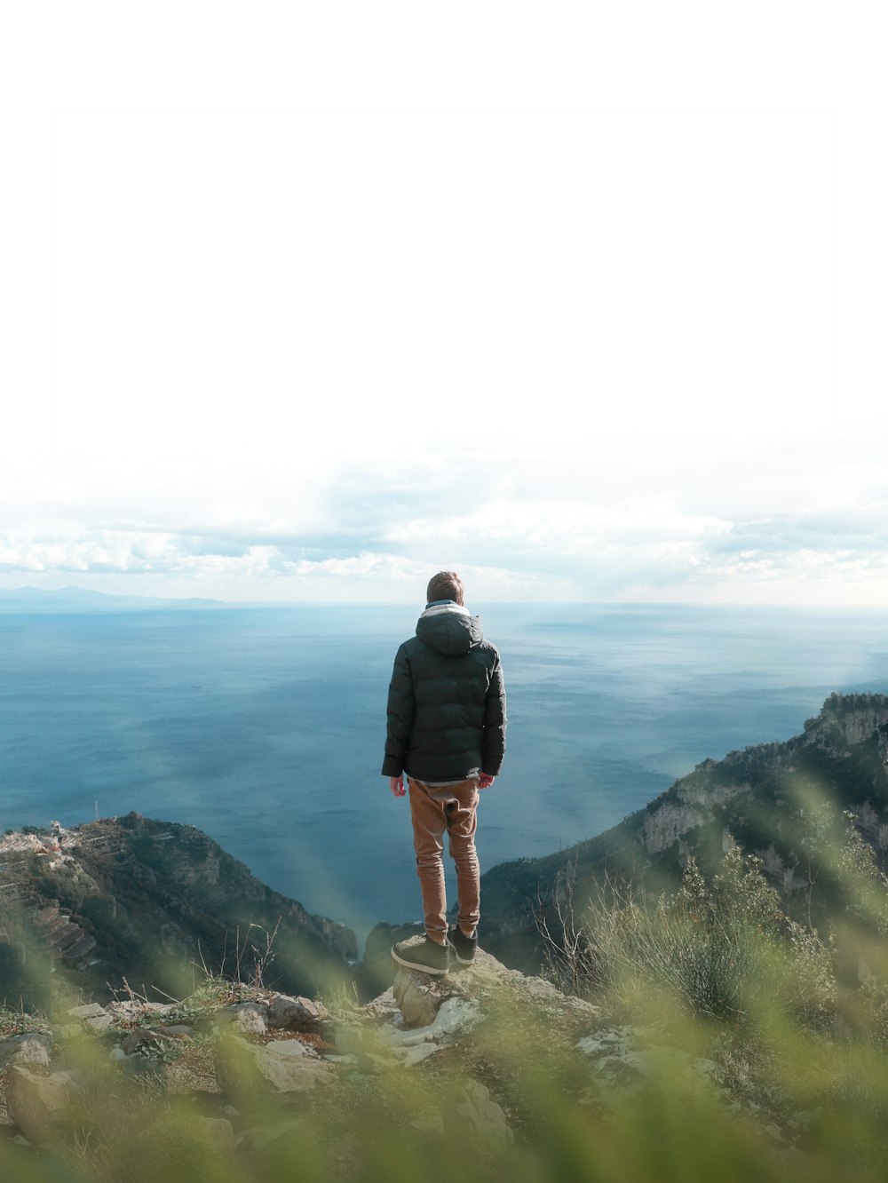 man in black jacket standing on cliff during daytime