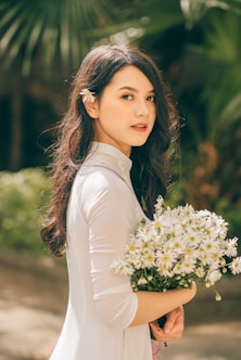 woman in white long sleeve shirt holding bouquet of flowers