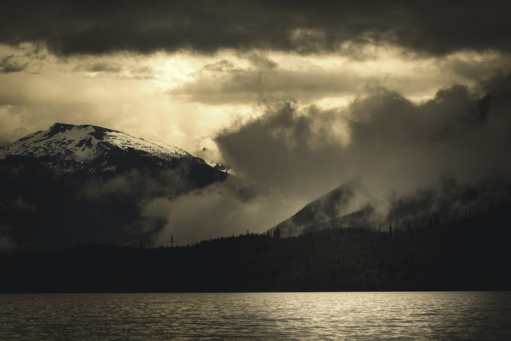 Photo en niveaux de gris d’une montagne près d’un plan d’eau