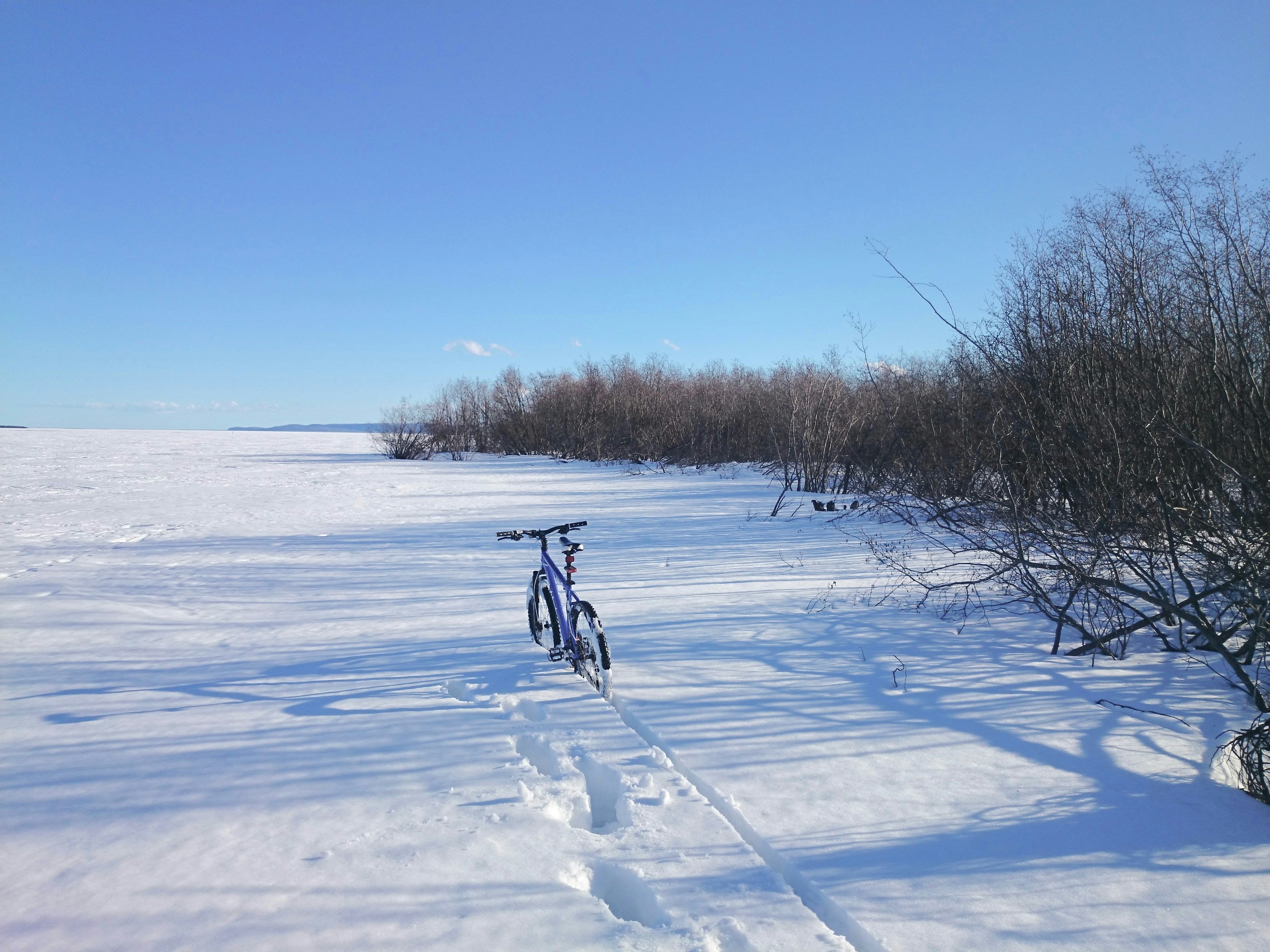 person riding on bicycle on snow covered field during daytime